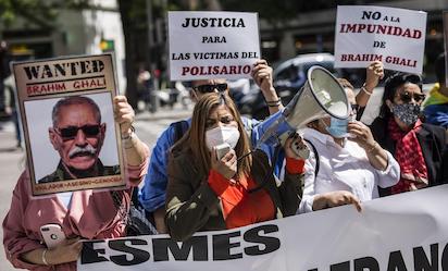 una mujer con un megafono acompanada de varias personas con carteles protestan contra el lider del frente polisario en la puerta de la audiencia nacional a 7 de mayo de 2021 ep